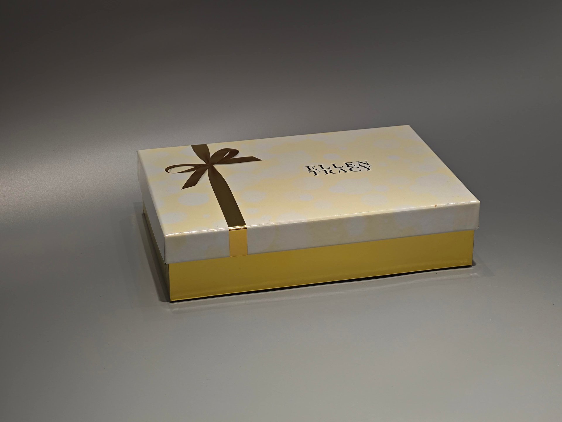 A closed lift-off lid box adorned with a luxurious gold ribbon. The design highlights elegance and sophistication, making it ideal for premium products.