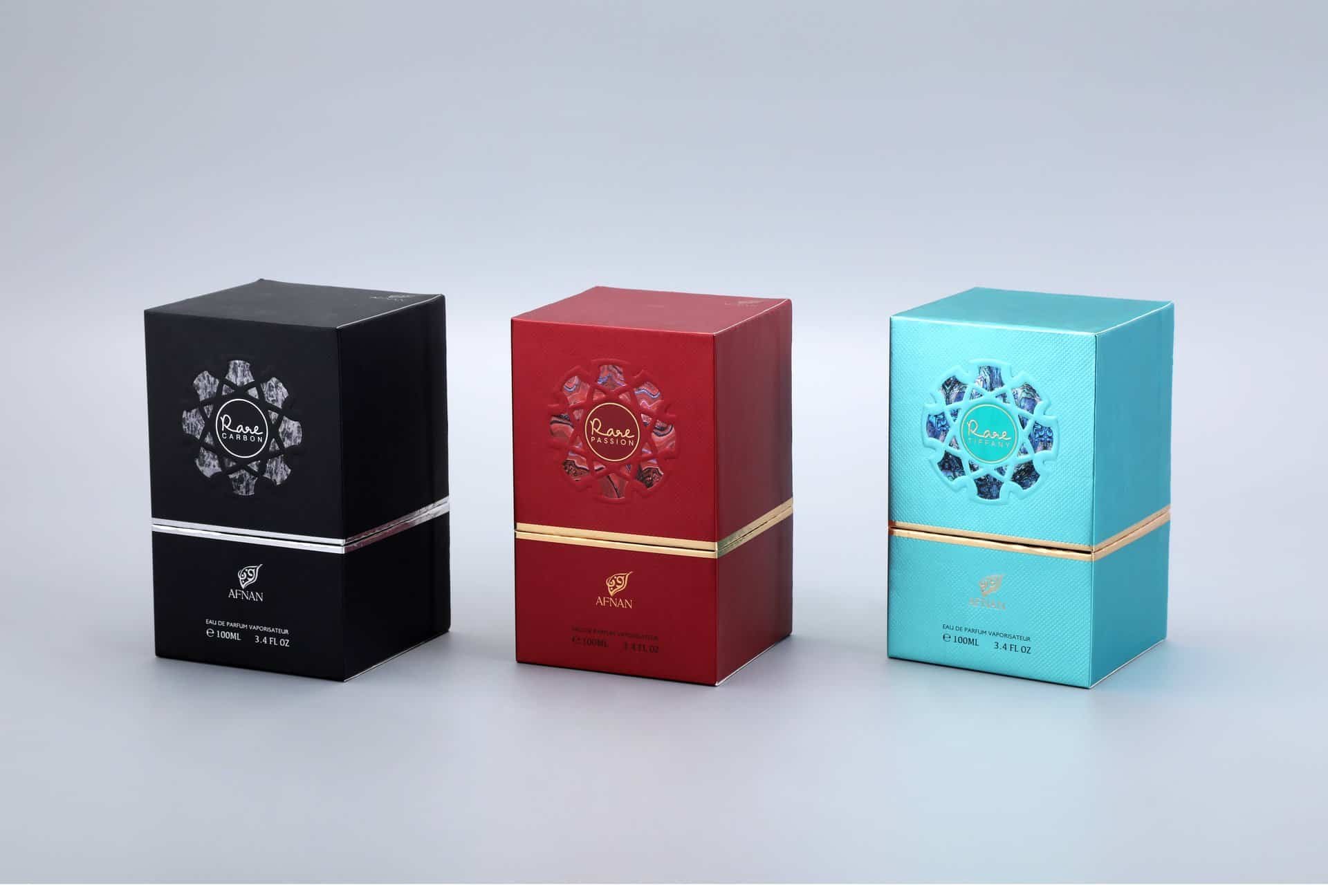 The image showcases three custom-designed perfume boxes arranged side by side. Each box features a distinct color scheme—black, red, and turquoise—and is adorned with an elegant decorative pattern. The front of each box displays a unique logo design, enhancing the overall aesthetic appeal while maintaining brand alignment.