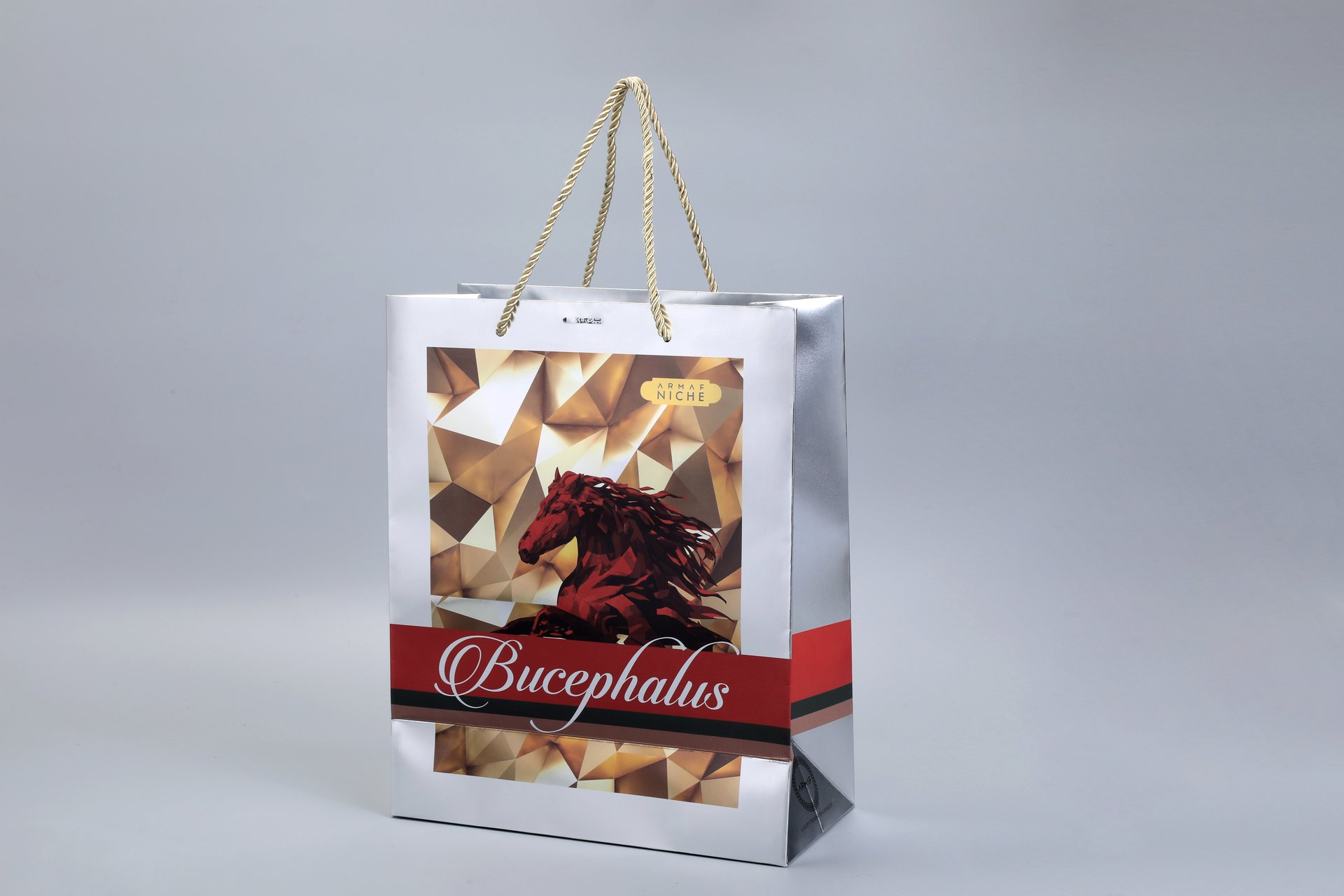 We are a manufacturer of custom box packaging. The design features a silver box with a gold geometric pattern and an artistic red horse motif. A red band at the bottom completes the look, offering ample space for brand or product labeling, without displaying any specific text.